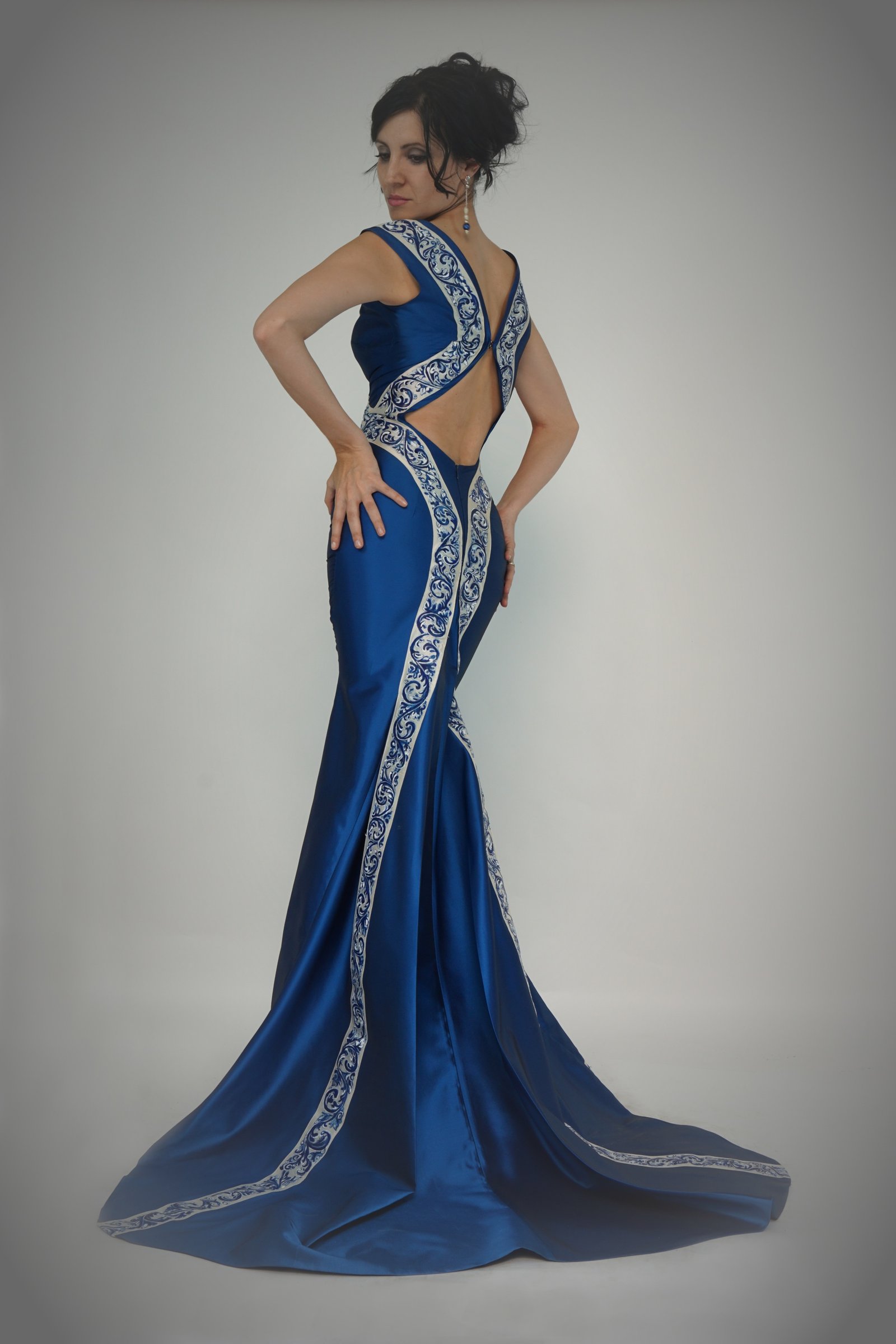 Vestido de alta costura en raso azul con cenefas bordadas, sobre modelo.